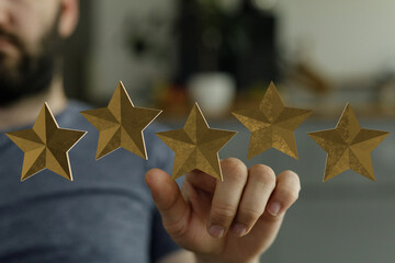 A close-up of a hand touching five golden stars, implying a rating or feedback system. Concept of...