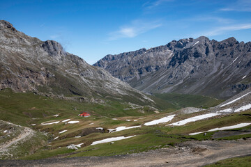 Dramatic mountain landscape with snow-capped peaks and a cozy red-roofed cabin, perfect for...