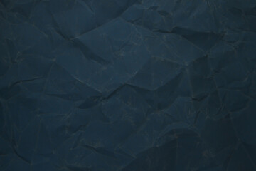 Obraz premium Dark blue crumpled paper texture background with soft light and deep folds