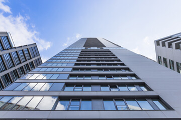 Modern glass skyscraper from below against blue sky, contemporary urban architecture