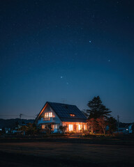 Nighttime house exterior with softly lit windows and rooftop solar panels under stars