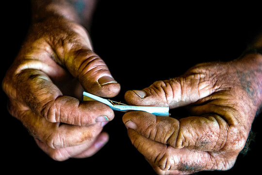 Hands rolling a cigarette with tobacco.