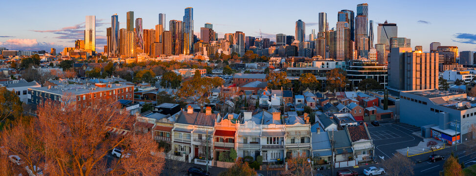 Aerial panorama of terrace houses in a suburban street in front of a city skyline in golden light