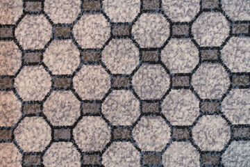 Textured carpet surface with repeating octagonal pattern in shades of grey and blue, forming a geometric grid design.