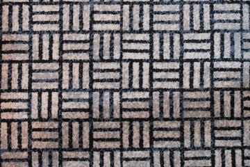 Close up of geometric patterned carpet with repeating square and line design in neutral tones.