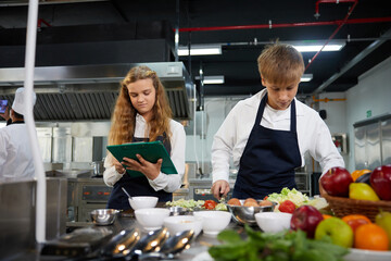 young chef cooking some food and preparing vegetable salad in the kitchen