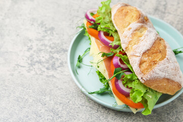 Delicious ciabatta sandwich with prosciutto, cheese and vegetables on light grey table, closeup. Space for text
