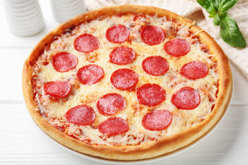 Delicious pepperoni pizza and ingredients on white wooden table, closeup