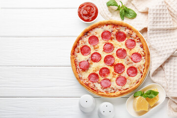 Delicious pepperoni pizza and ingredients on white wooden table, flat lay. Space for text