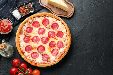 Delicious pepperoni pizza and ingredients on black table, flat lay. Space for text