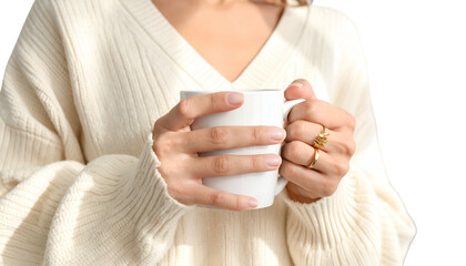 A person holds a white mug in both hands, wearing a sweater and rings