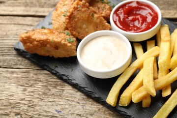 British Traditional Fish and chips with sauces on wooden table, closeup. Space for text
