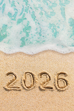 New Year 2026 handwritten on the beach with ocean wave and sand background, Hollidays concept photo