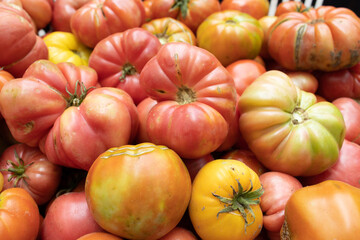Tight closeup of assorted heirloom tomatoes inside a crate. Natural colors and rustic texture for organic food and farm harvest uses.