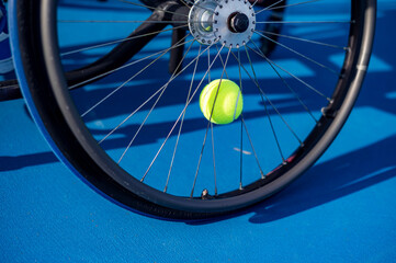 A vibrant yellow tennis ball on a wheelchair on a blue court during a match