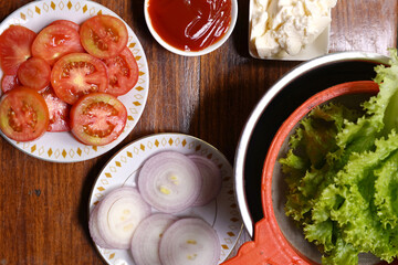 Salad leaves with tomatoes slices and onion slices on wood table. tomato sauce and mayonnaise