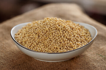 A white bowl filled with couscous sits on a burlap cloth, showcasing the small grain texture