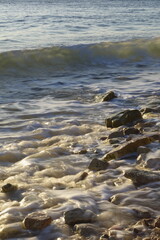 Waves crashing on a rocky shoreline at golden hour, creating a beautiful seascape