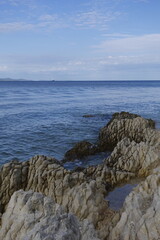 coastal landscape with rocky shore and calm blue sea under a cloudy sky