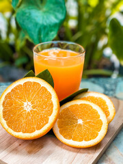 A glass of fresh orange juice with whole oranges placed beside it, refreshing and full of vitamin C, perfect for breakfast or a healthy lifestyle concept.