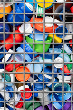 Colorful plastic bottle caps in metal recycling cage