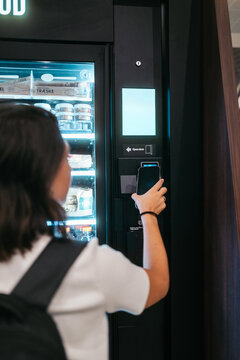 Woman using vending machine with smartphone in Copenhagen