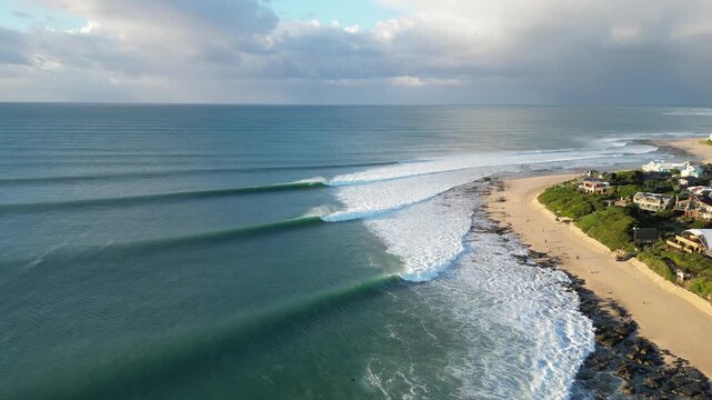Aerial view of perfect ocean waves with surfers surfing at Supertubes point break in Jeffreys Bay or J-Bay in South Africa.