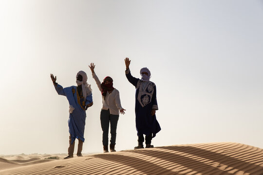Tourist and guides waving in the Sahara Desert in Morocco