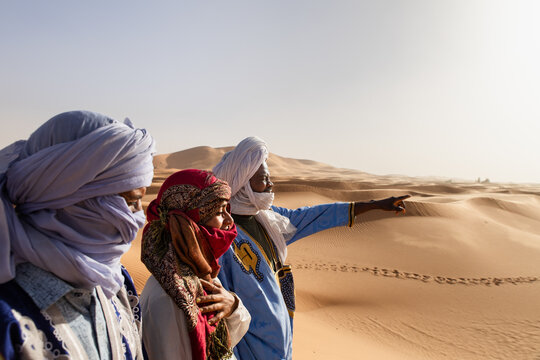 Tourist with travel guides exploring sand dunes in the Sahara desert
