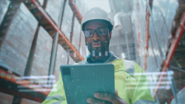 African American industrial worker in helmet and reflective jacket holding tablet with holographic projection. Male supervisor checking digital inventory in large warehouse with stacked pallets.