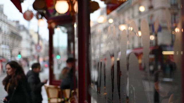 Paris street scene through cafe window featuring people, bus, architecture and city life in France.