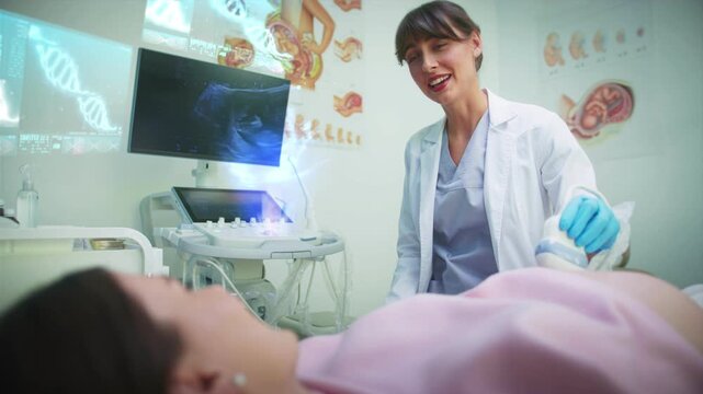 Female doctor in lab coat performing ultrasound examination on pregnant woman. Holographic medical projections showing fetal scan and genetic data in bright clinic. Medical technology concept.