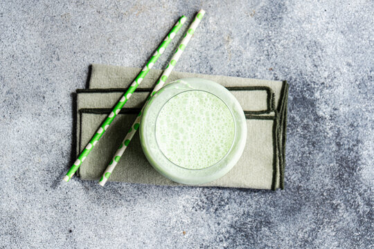 Refreshing matcha latte with straws on a gray background