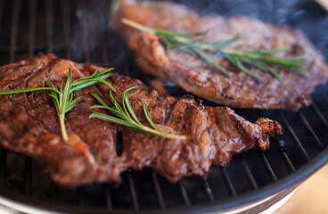 Grilled entrecote steaks with rosemary on charcoal grill, smoke