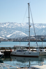White sailing catamaran moored in marina with snowy mountains background winter