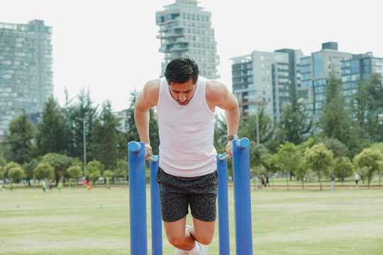 Man working out on parallel bars in urban park