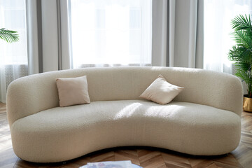 Soft curved sofa in light upholstery with soft corners for a large and bright room. Minimalism,