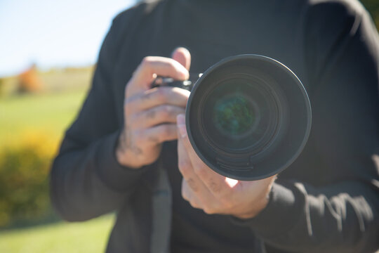 Photographer holding a digital camera taking pictures in nature.