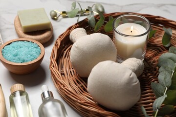 Composition with spa products, burning candle and eucalyptus branches on white marble table, closeup