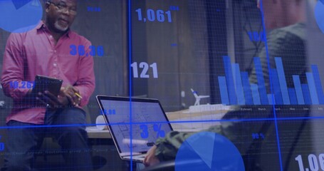 Presenting senior man holding tablet facing woman on laptop in office, with floating digital charts © vectorfusionart