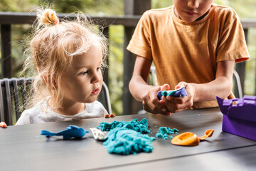 Children playing creatively with kinetic sand on terrace