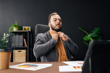 Confident businessman adjusting shirt collar in office preparing for work