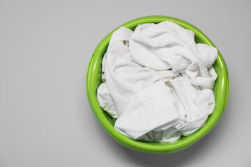 Plastic basin with clothes on light grey background, top view. Space for text