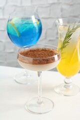 Glasses of tasty cocktails on white table, closeup