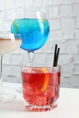 Glasses of tasty cocktails on white table, closeup