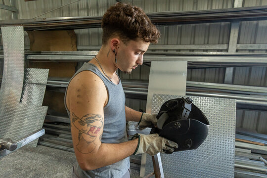 Trans man focused on welding in workshop setting