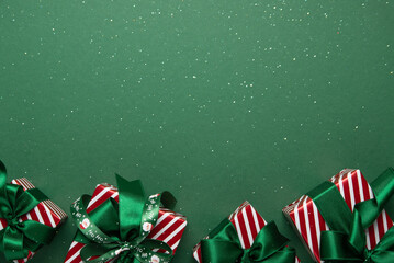 Merry Christmas and Happy Holidays greeting card, frame, banner. New Year. Red white Christmas ornaments and gifts, presents on green background top view. Xmas holiday festive theme.