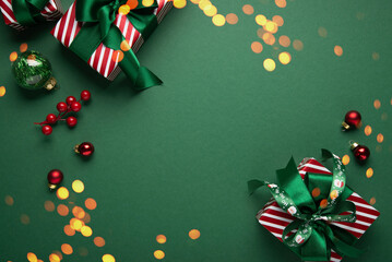 Merry Christmas and Happy Holidays greeting card, frame, banner. New Year. Red white Christmas ornaments and gifts, presents on green background top view. Xmas holiday festive theme.