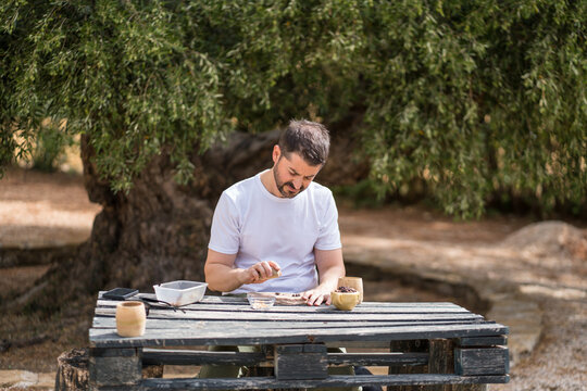 Man cracking pine nuts at a rustic outdoor table