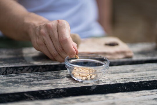 Man cracking pine nuts over rustic table